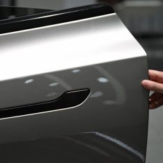 A woman opens the door for a Tesla Model YL electric vehicle at a showroom in Beijing on February 3, 2026. China will ban hidden door handles on cars sold in the country from next year, phasing out the minimalist design popularised by Tesla over safety concerns. (Photo by Pedro Pardo / AFP)