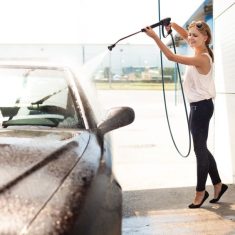 47251211 - young woman washing the car smiling.