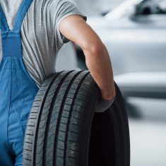 Repair concept. Mechanic holding a tire at the repair garage. Replacement of winter and summer tires