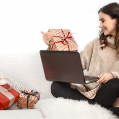 Beautiful woman with computer and Christmas gifts.