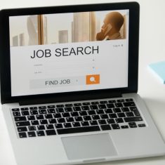 Open laptop on the desk, job search title on screen