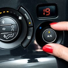 Woman turns on air conditioning in a car