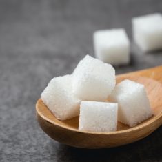 white Sugar cube in wood spoon on table.