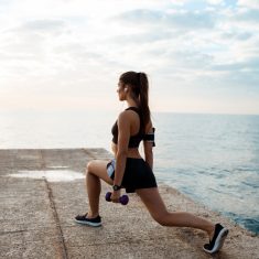 Young beautiful sportive girl training at sunrise over seaside.