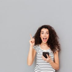 Smart female with mobile phone in hand keeping index finger poin