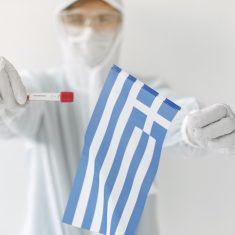 The scientist in coverall suit with a coronavirus sample and Greek flag