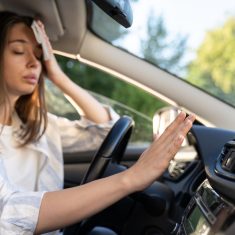Woman driver has problem with a non-working conditioner, hand checking flow cold air, being hot during heat wave in car, suffering from summer hot weather, wipes sweat from her forehead with tissue.