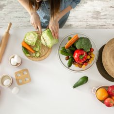 A young woman is preparing a salad in the kitchen .
