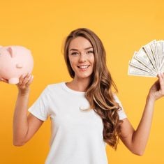Portrait of a cheery young girl holding piggy bank