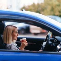 Lovely woman driving satisfied with coffee to go